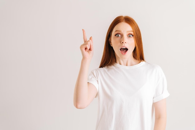 Portrait of cheerful pretty young woman open mouth having idea pointing with finger up looking at