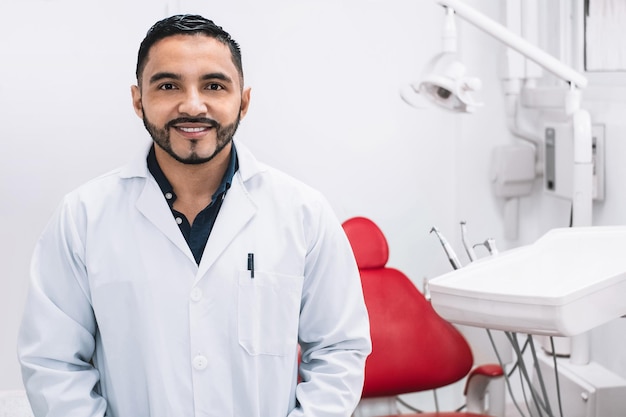 Portrait of cheerful and smiling Hispanic dentis in a clinic