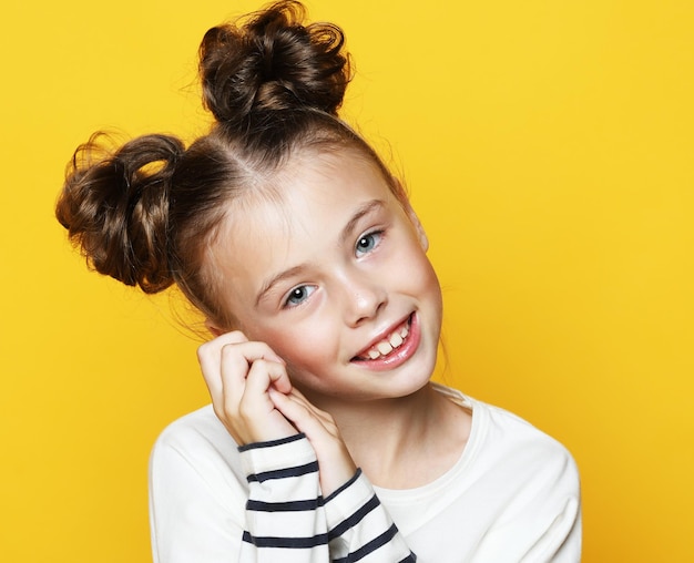 Portrait of cheerful smiling little girl on yellow background