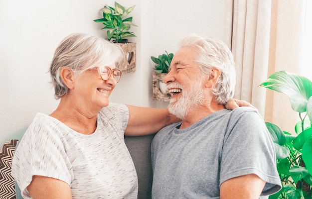 Portrait of cheerful whitehaired senior family couple laughing sitting at home