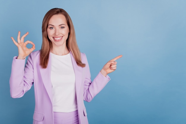 Portrait of cheerful woman direct finger empty space show okey sign