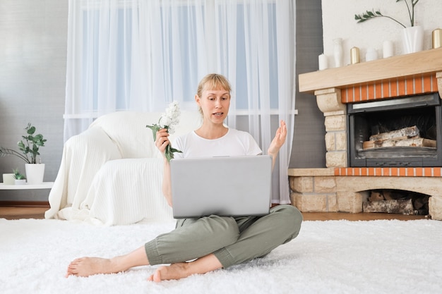 Portrait of a cheerful woman at home with a laptop, connected online to a meeting with friends.