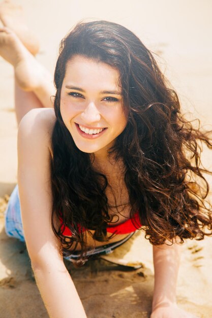 Portrait of cheerful woman lying at beach