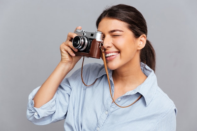 Ritratto di una donna allegra che fa foto con la parte anteriore isolata su un muro grigio