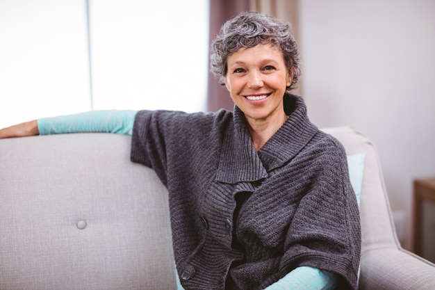 Portrait of cheerful woman sitting on sofa