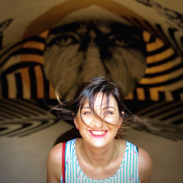 Portrait of cheerful woman with messy hair against wall