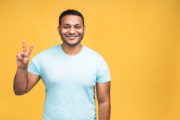 Portrait of a cheerful young african american indian black man standing isolated over yellow background.