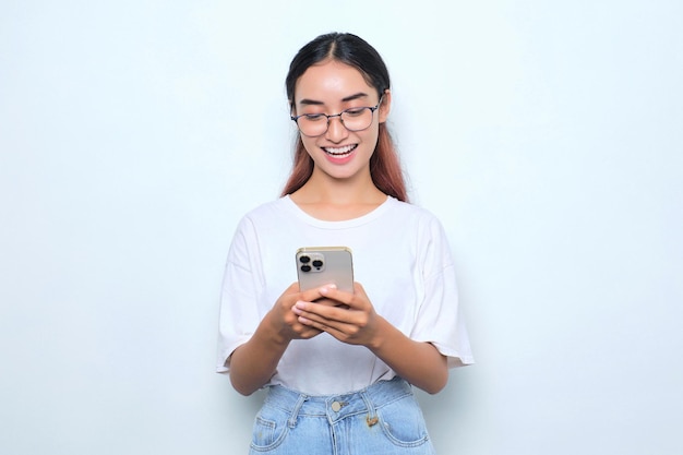 Portrait of cheerful young Asian girl in white tshirt using mobile phone isolated on white background