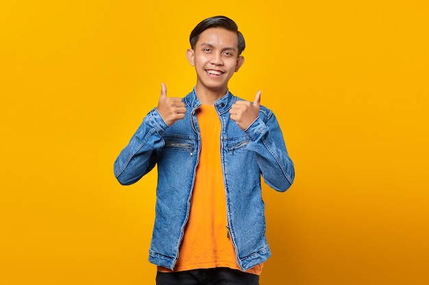 Portrait of cheerful young Asian man showing thumbs up or sign of approval