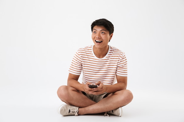 Portrait of a cheerful young asian man using mobile phone