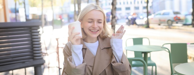 Foto ritratto di una giovane donna bionda allegra che si diverte a passare il tempo in un caffè all'aperto a bere caffè e