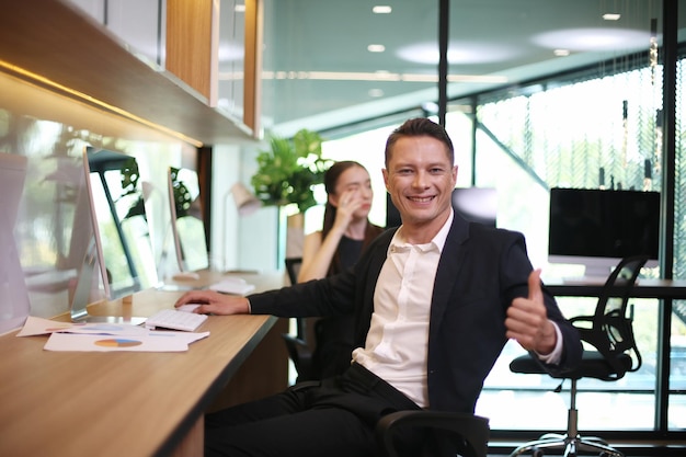 Portrait of cheerful young businessman give thumb up to camera