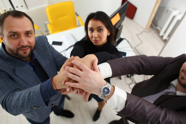 Portrait of cheerful young businessmen in office place their hands one over the other