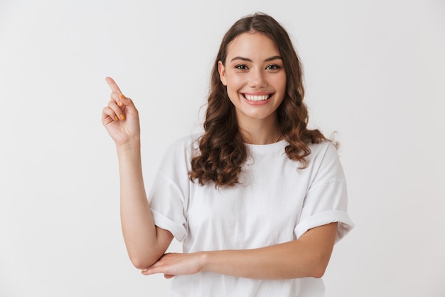 Portrait of a cheerful young casual brunette woman pointing