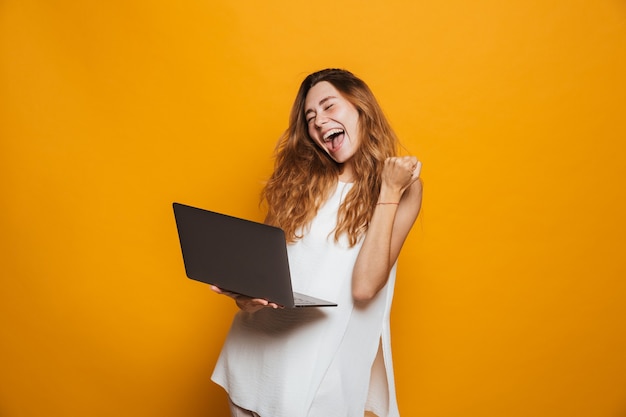 Portrait of a cheerful young girl holding laptop computer