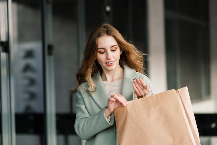 Photo portrait of a cheerful young lady holding shopping bags outdoor