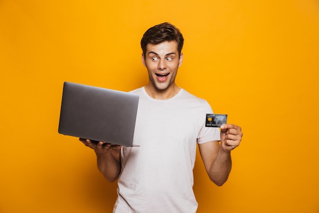 Portrait of a cheerful young man holding laptop computer