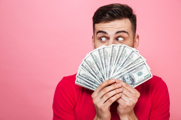 Photo portrait of a cheerful young man holding money banknotes