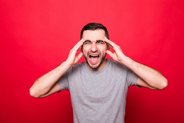 Portrait of a cheerful young man screaming standing isolated over red background