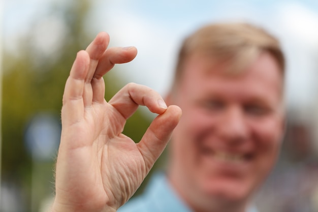 Portrait of cheerful young man showing okay gesture. Emotions and success concept.