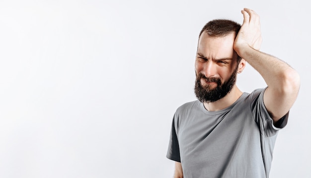 Portrait of cheerful young man smiling while looking at camera holding hands out to sides on white background with space for advertising mock up