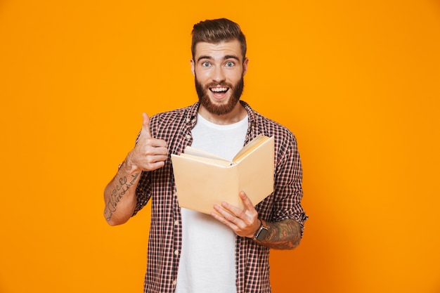 Portrait of a cheerful young man wearing casual clothes holding paper book