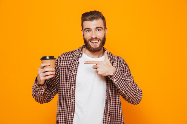 Portrait of a cheerful young man wearing casual clothes holding takeaway coffee