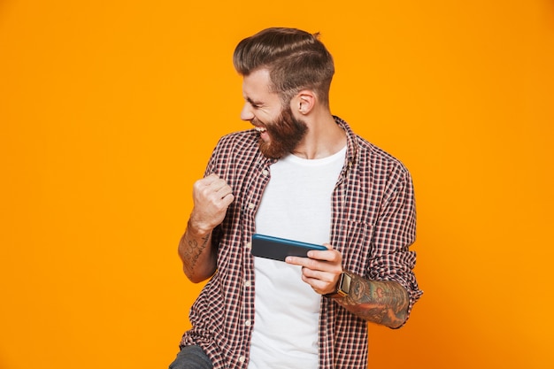 Portrait of a cheerful young man wearing casual clothes playing games on mobile phone