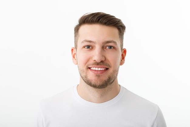 Portrait of a cheerful young man in a white Tshirt on a white background The guy is standing looking at the camera and smiling