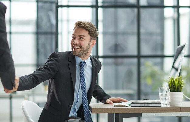 Portrait of cheerful young manager handshake with colleague