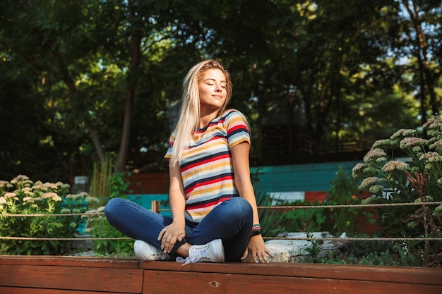 Portrait of a cheerful young teenage girl sitting on a bench