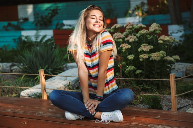 Portrait of a cheerful young teenage girl sitting on a bench