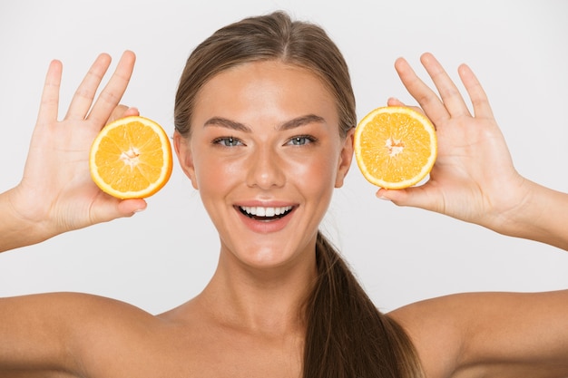 Portrait of a cheerful young topless woman isolated, showing sliced orange