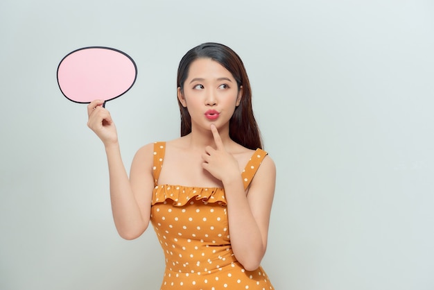 Portrait of a cheerful young woman holding a blank speech bubble
