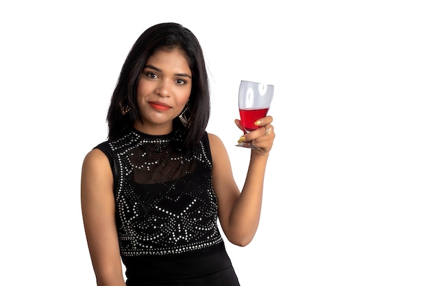 흰색 배경에 격리된 와인 한 잔을 들고 있는 쾌활한 젊은 여성의 초상화