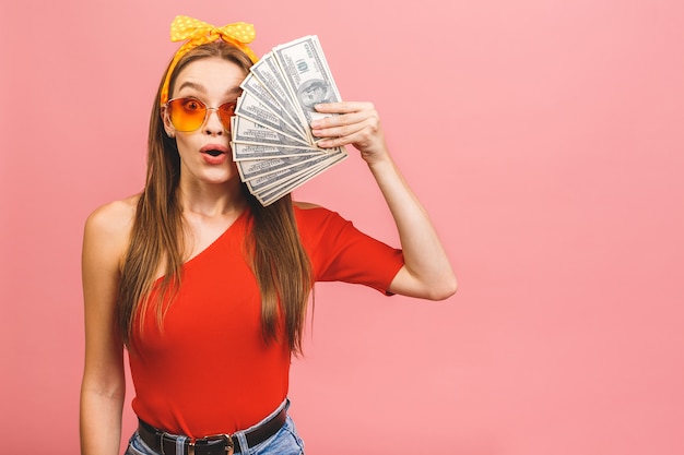 Photo portrait of a cheerful young woman holding money banknotes and celebrating