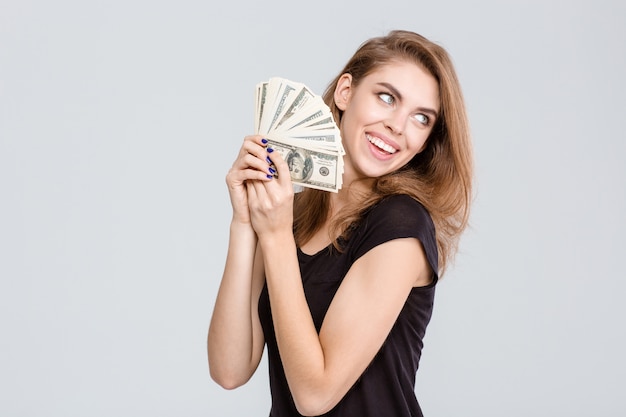 Portrait of a cheerful young woman holding money isolated on a  white background