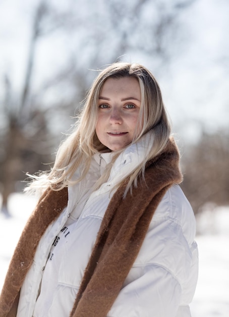 Ritratto giovane donna allegra in vestiti caldi da inverno che si diverte nella foresta invernale tra gli alberi