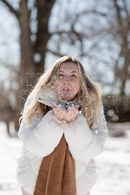 Foto ritratto giovane donna allegra in vestiti caldi da inverno che si diverte nella foresta invernale tra gli alberi