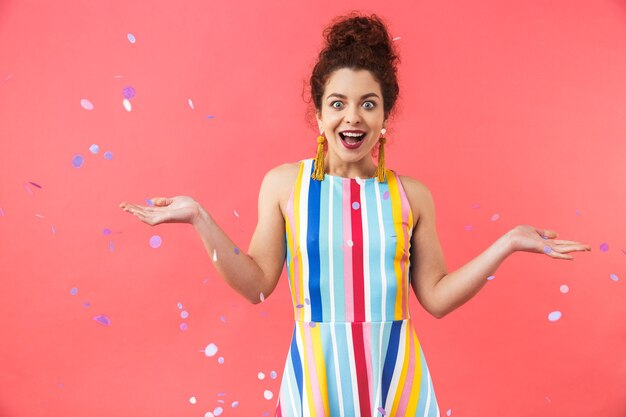 Photo portrait of a cheerful young woman wearing dress standing isolated over red background