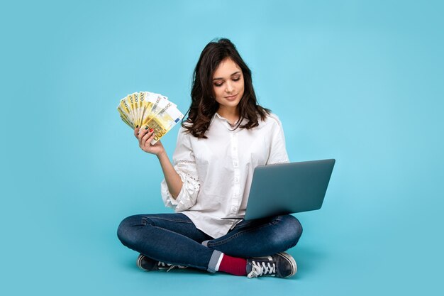 Foto ritratto di una bella ragazza allegra che indossa un abito e occhiali da sole tenendo i sacchetti della spesa e mostrando la carta di credito isolato su sfondo blu