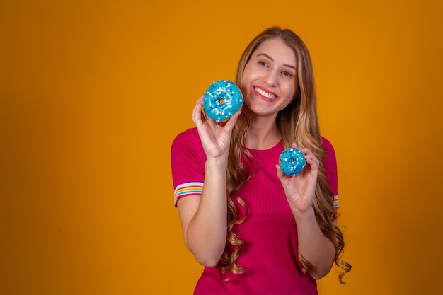 Portrait of a cheery pretty girl holding blue donuts at her face