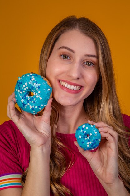 Portrait of a cheery pretty girl holding blue donuts at her face