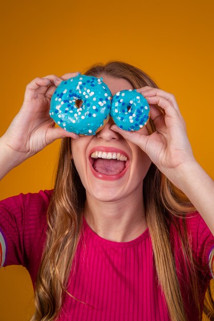 Portrait of a cheery pretty girl holding blue donuts at her face