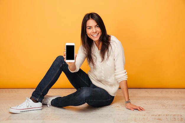 Portrait of a cheery young woman sitting on a floor