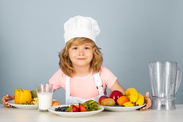 Portrait of chef child in cook hat cooking at home kid boy preparing food from vegetable and fruits