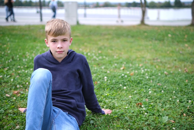 Portrait of child boy outdoors resting on grass lawn