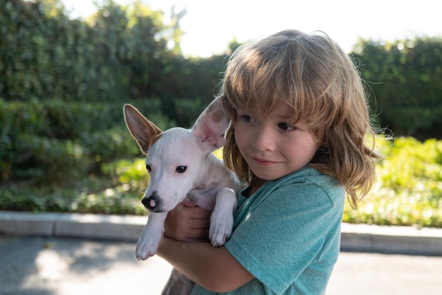 子供の肖像画は犬と遊ぶ屋外の子供は愛情を込めて彼のペットの犬を抱きしめます