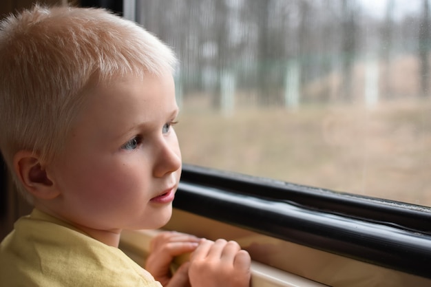 窓際の電車の中で子供の男の子の肖像画