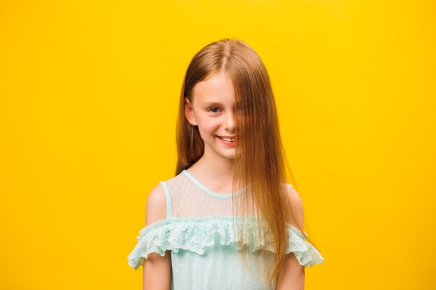 카메라를 바라보는 백인 소녀의 초상화, 노란색 배경에 미소 짓는 아이의 얼굴
